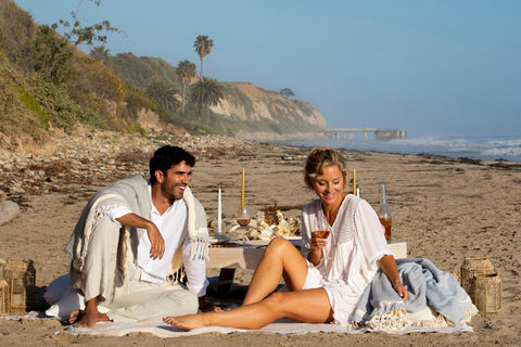 A couple sharing blankets at a beach picnic at sunset