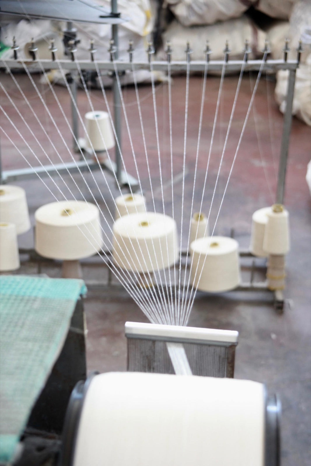 Cotton yarn cones feeding fine threads onto a loom at a mill in Turkey