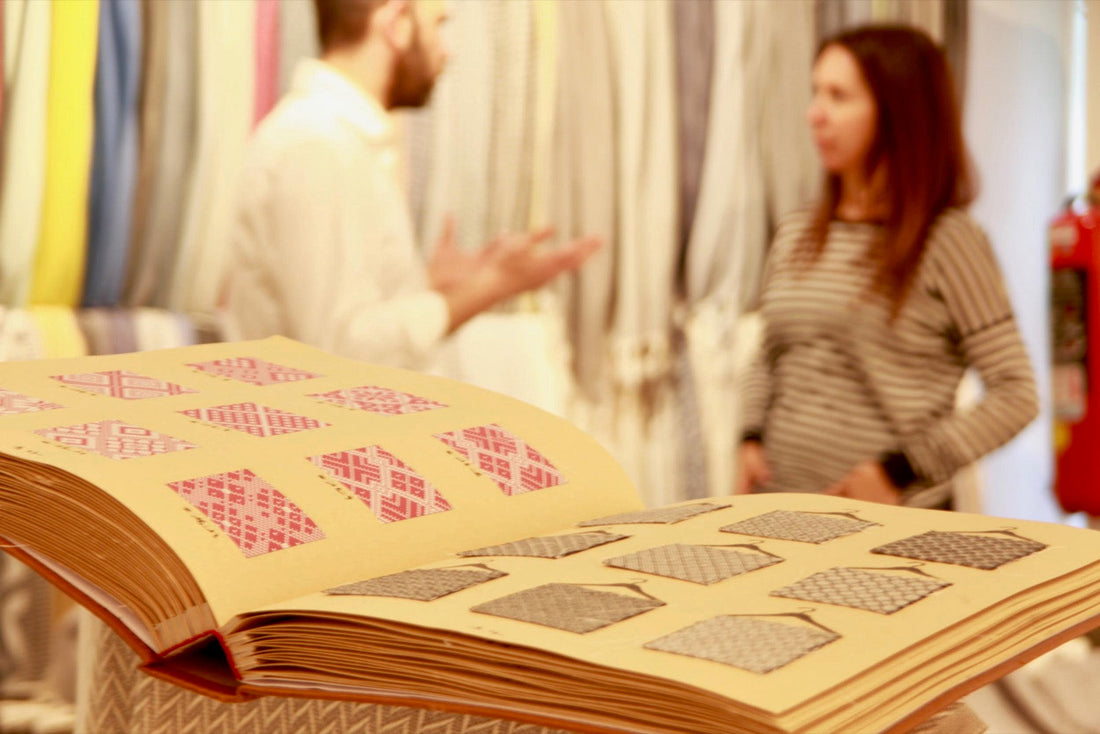 A pattern book of woven samples being reviewed by two people at a mill in Turkey