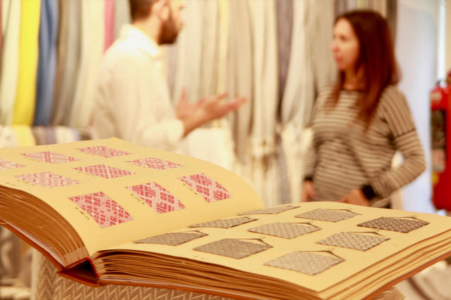 A pattern book of woven samples being reviewed by two people at a mill in Turkey