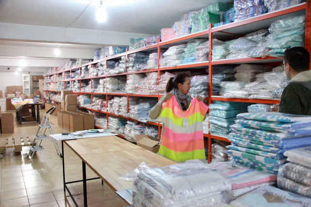 A warehouse with shelves of finished towels and a work table