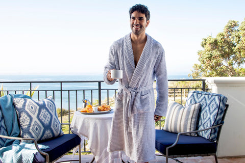 A couple in waffle robes having breakfast on a seaside terrace