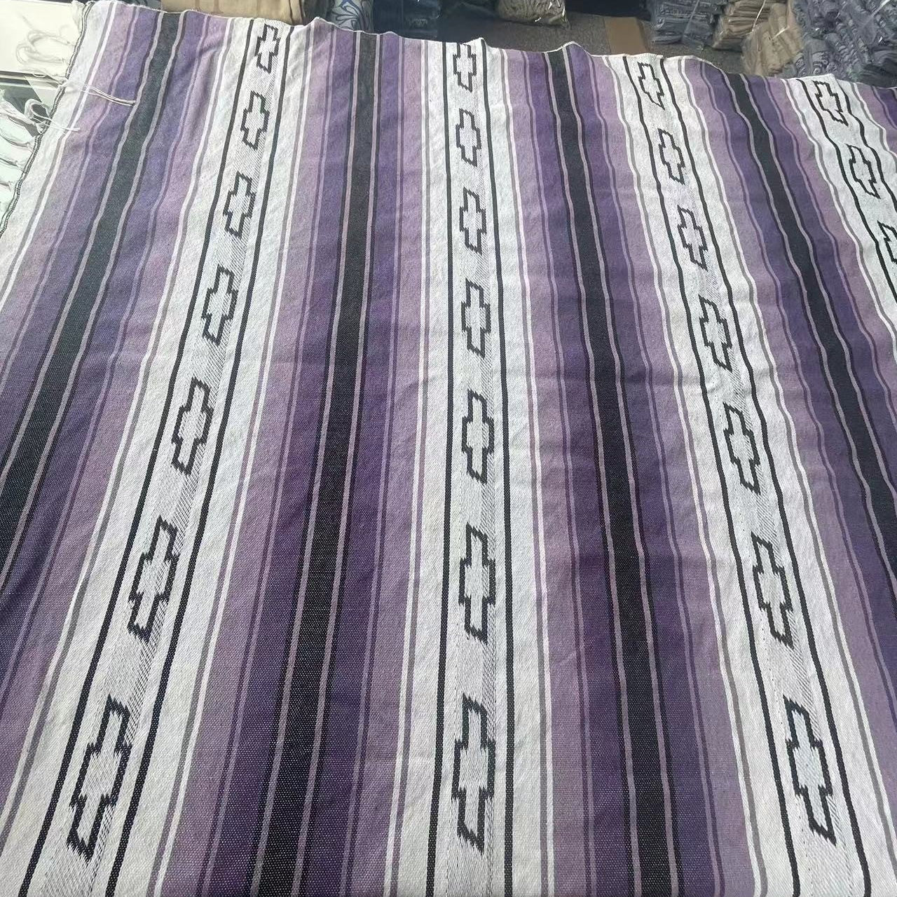 Purple and white striped fabric with geometric patterns on a table.