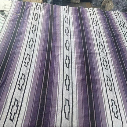 Purple and white striped fabric with geometric patterns on a table.