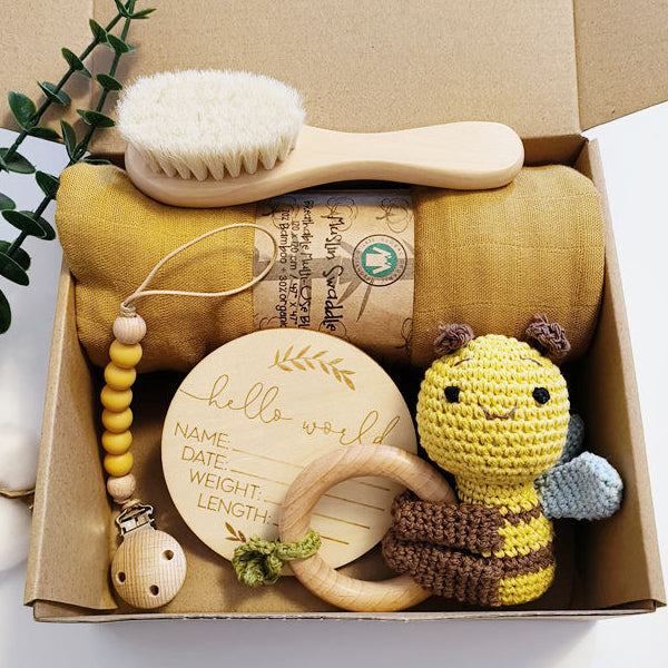 Baby care product set including a brush, toy, and milestone card in a box.