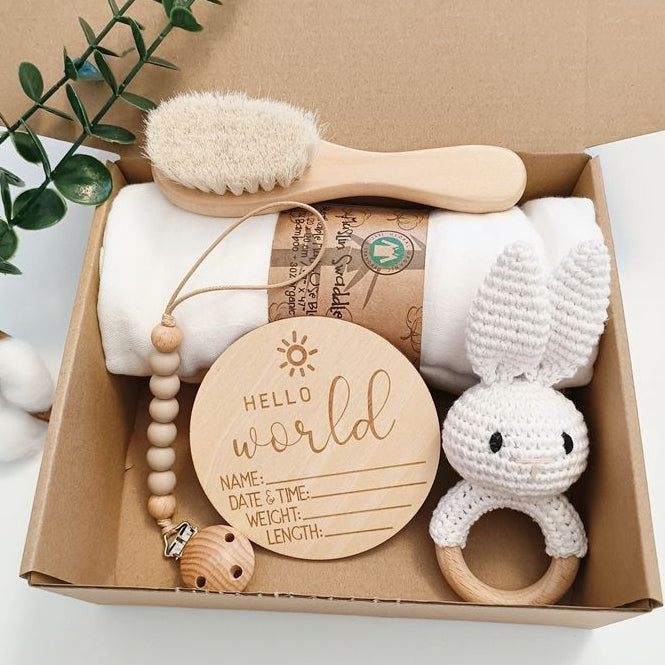Baby gift set with wooden rattle, brush, and milestone card in a box.