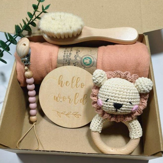Baby gift set with lion rattle, wooden brush, and other items in a box.