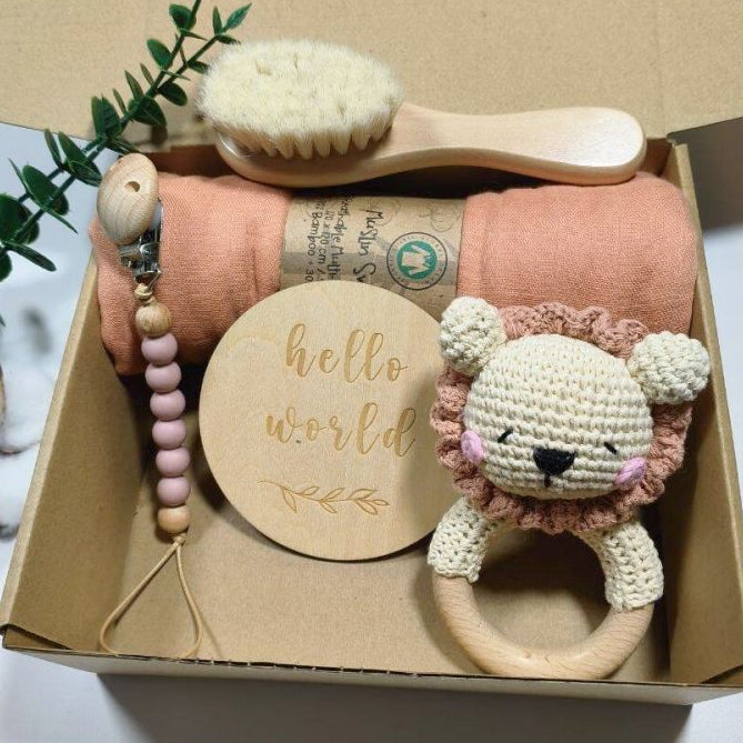 Baby gift set with lion rattle, wooden brush, and other items in a box.