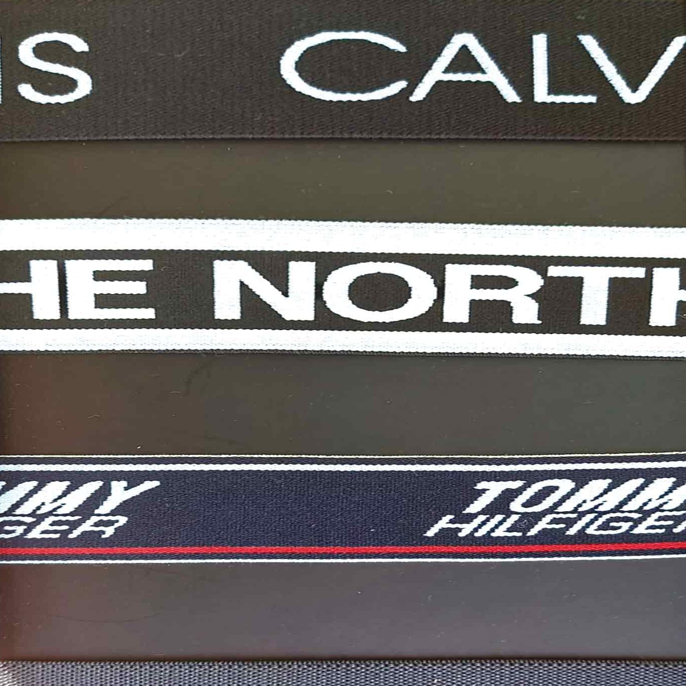 Close-up of woven labels from Calvin Klein, The North Face, and Tommy Hilfiger.