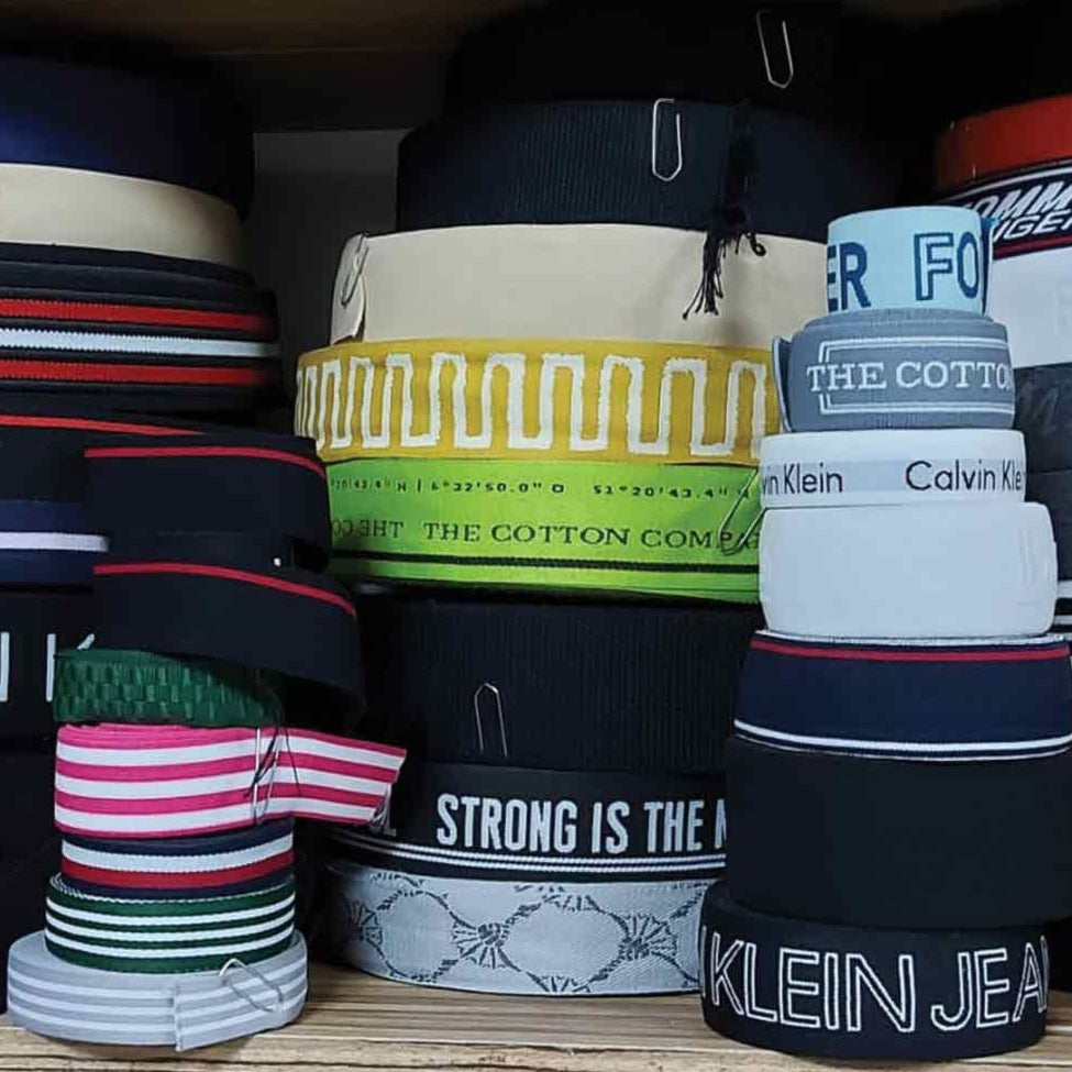 Stacks of various branded belts on a shelf