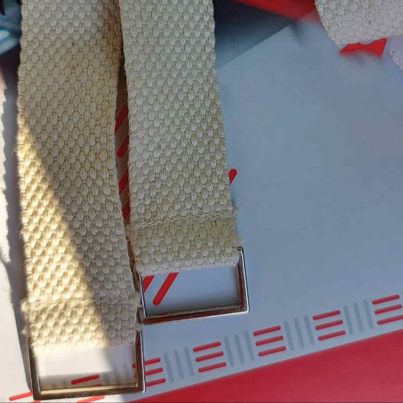 Beige belt with a metal buckle on a red and white striped background