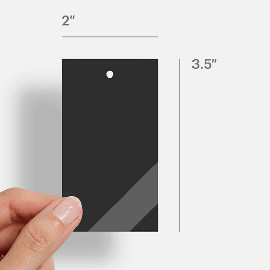 Hand holding a small black square with measurements on a white background