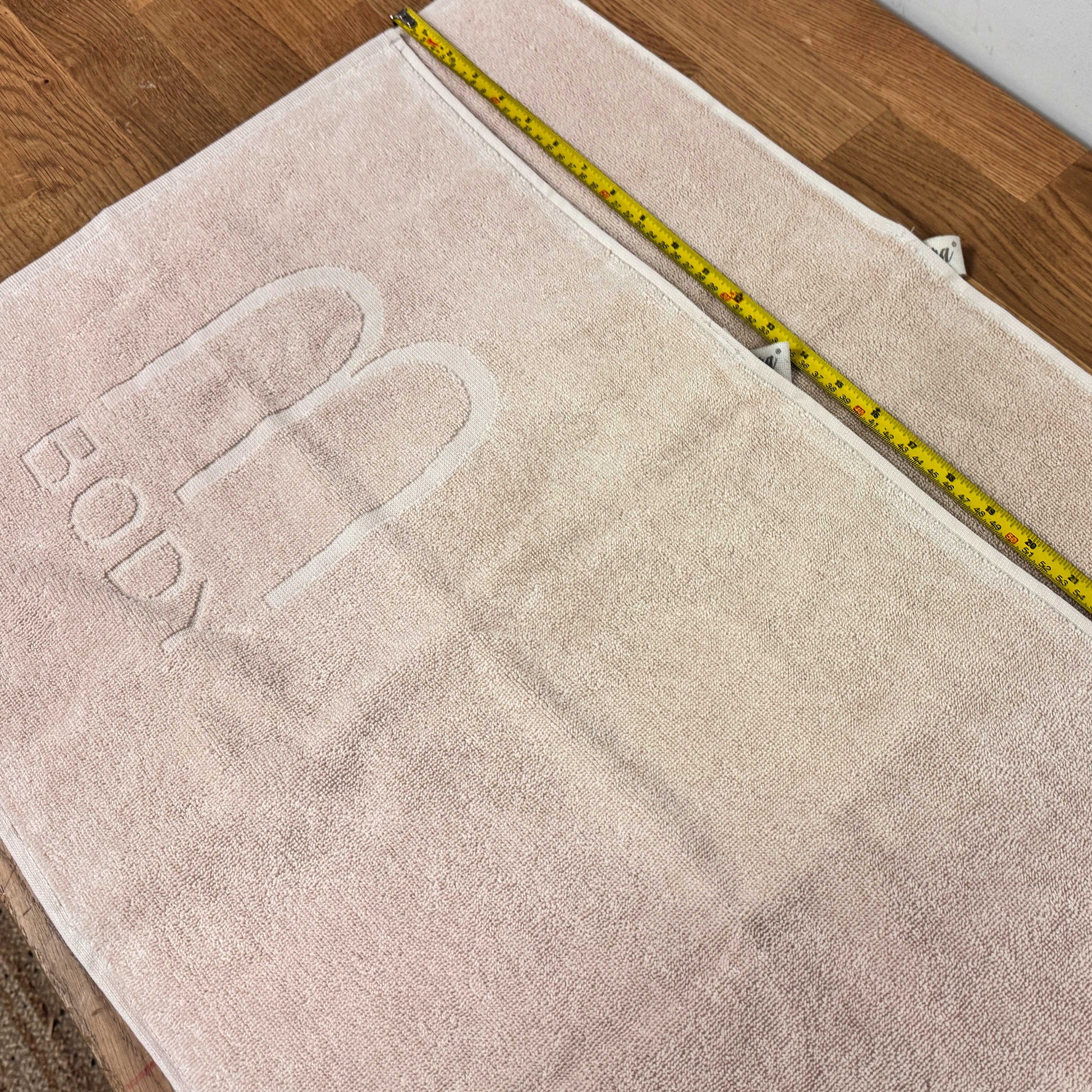 Beige towel with Relief or Debossed branding on a wooden floor