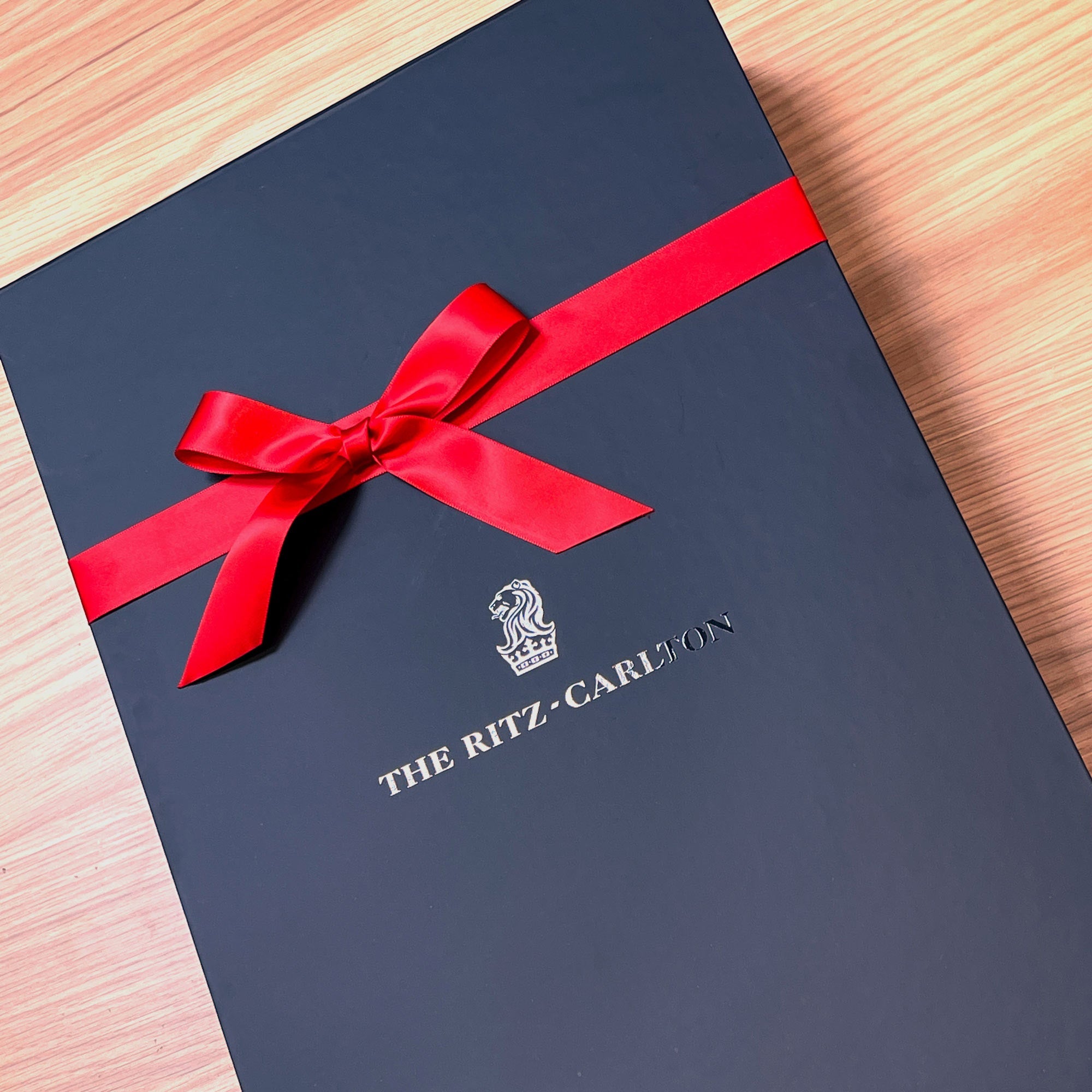 Black gift box with a red ribbon and 'The Ritz-Carlton' logo UV printed. Soft touch gift box with magnetic closure and perfect ribbon.