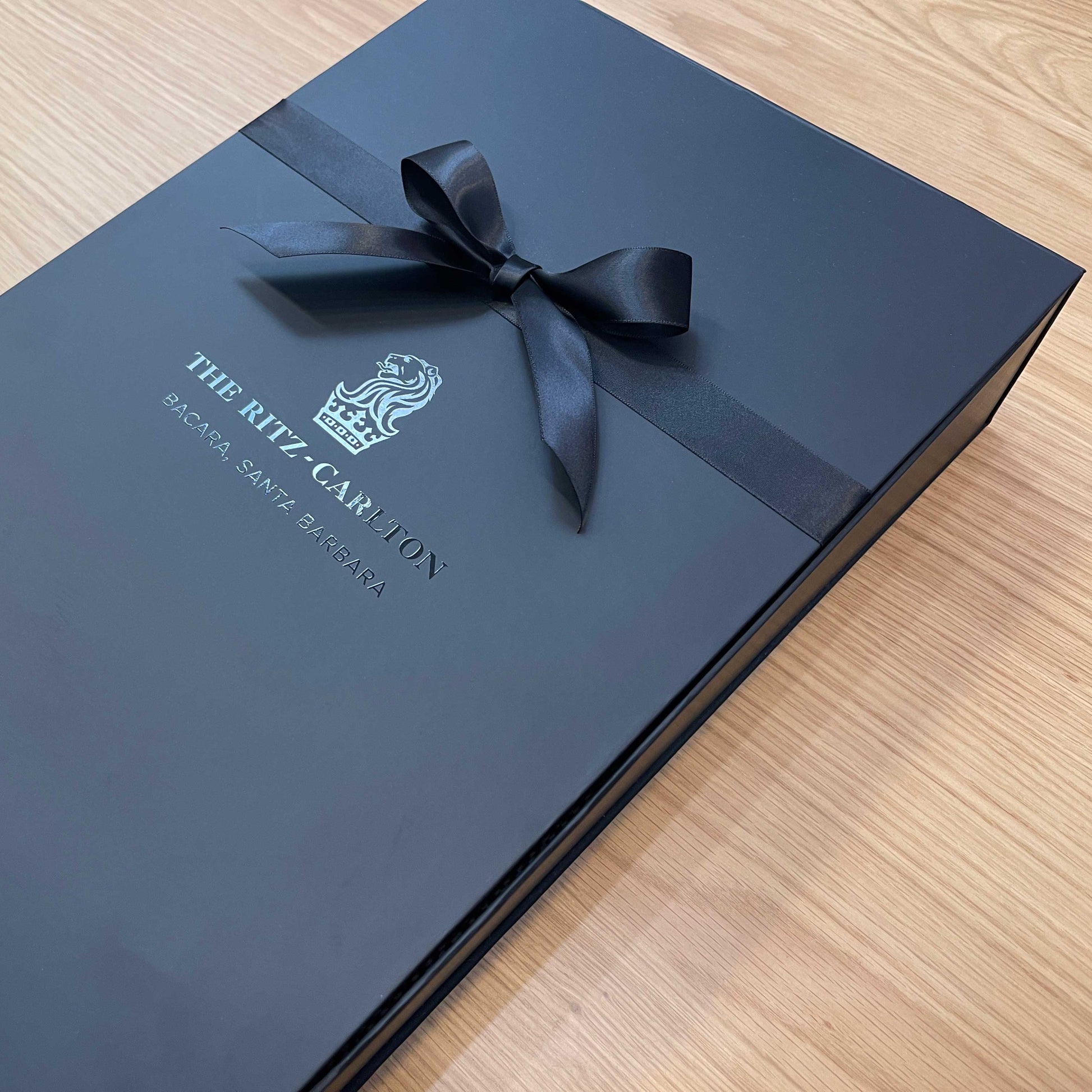 Black gift box with a black ribbon with UV printed logo, for The Ritz-Carlton. With soft touch coating and magnetic closure. 
