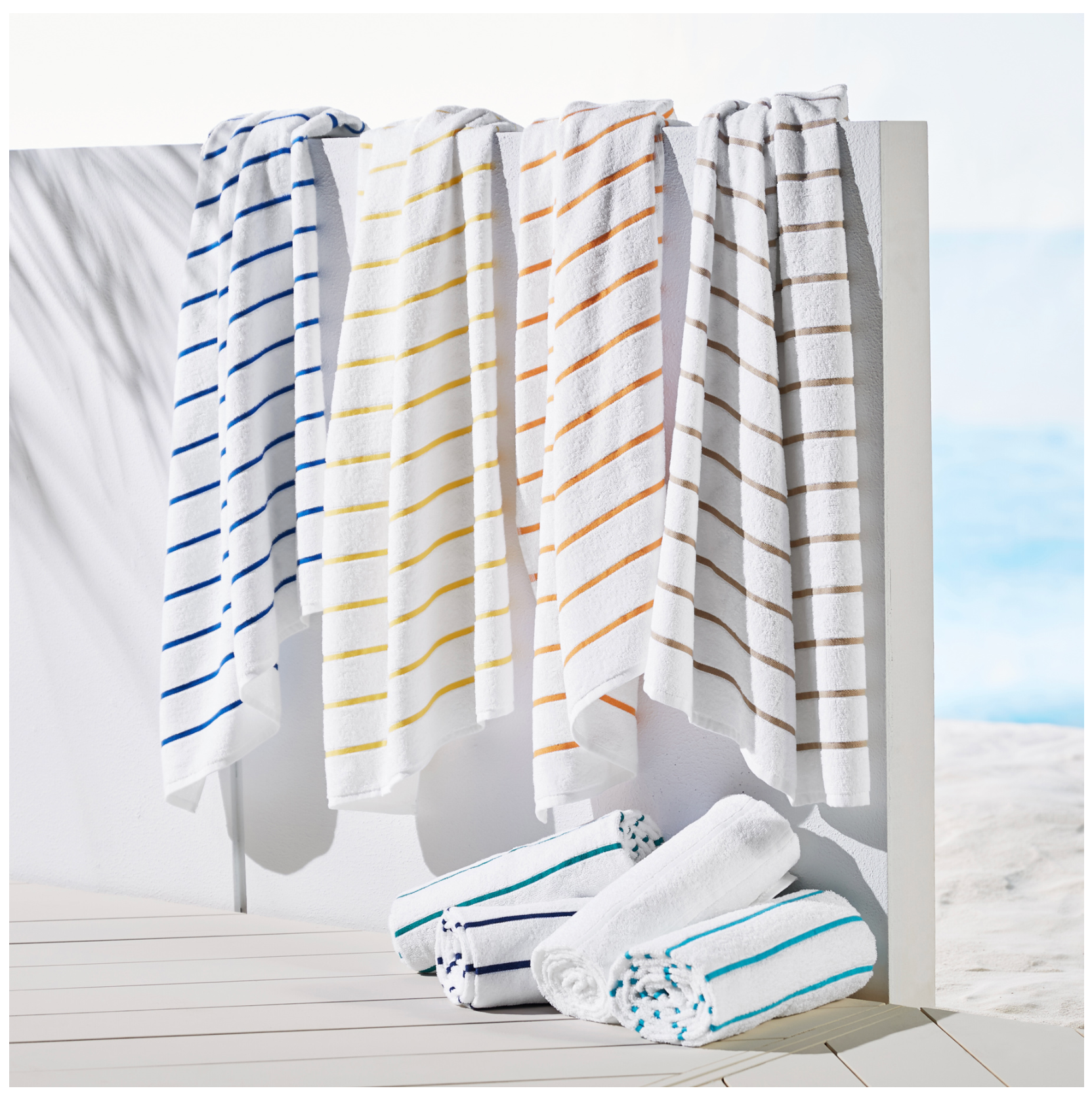 Set of striped towels hanging on a rack with a clear sky background