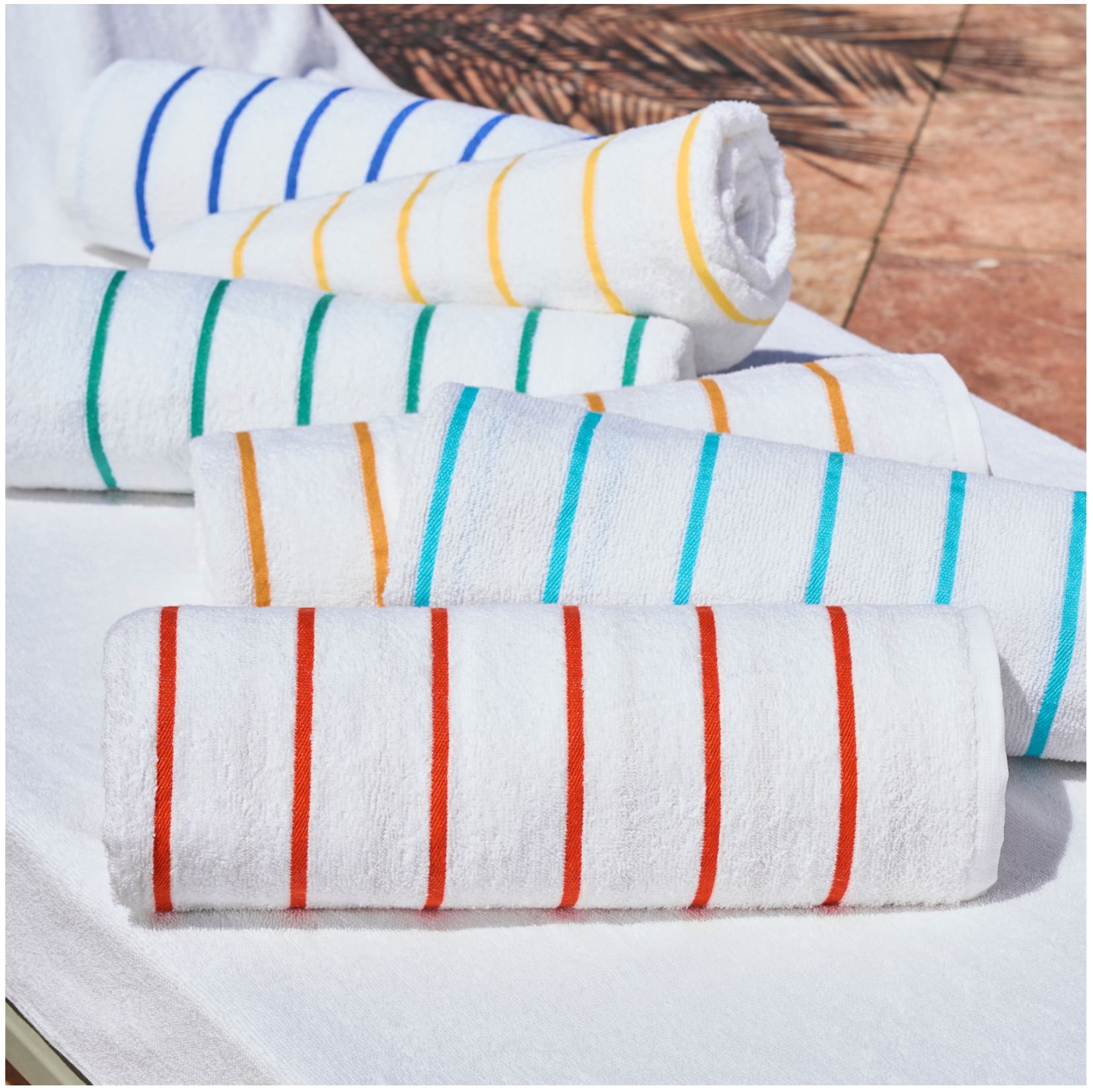 Set of rolled-up towels with colorful stripes on a wooden surface
