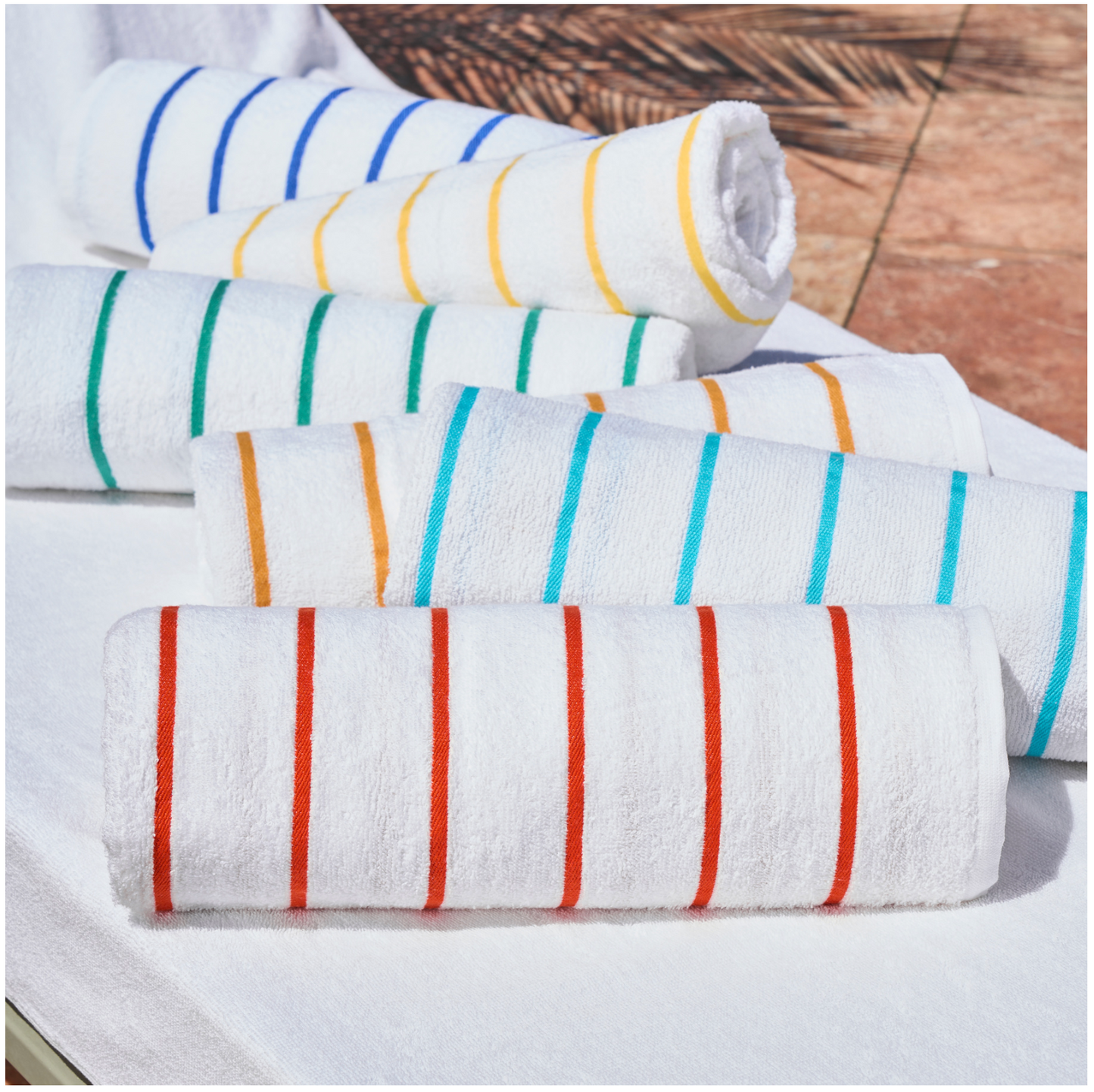 Set of rolled-up towels with colorful stripes on a wooden surface