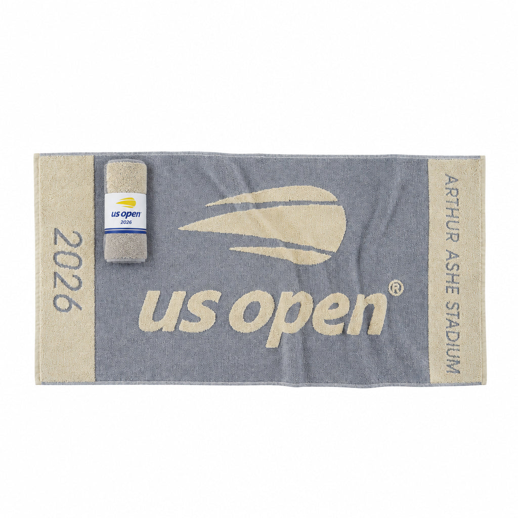 A navy and beige US Open tennis towel featuring 'Arthur Ashe Stadium', the US Open logo, and '2026' text, shown with a matching packaged towel on a white background.