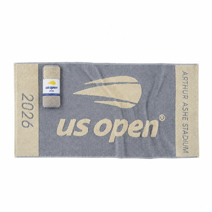 A navy and beige US Open tennis towel featuring 'Arthur Ashe Stadium', the US Open logo, and '2026' text, shown with a matching packaged towel on a white background.