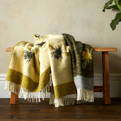 Two patterned throw blankets draped over a wooden bench against a neutral wall.