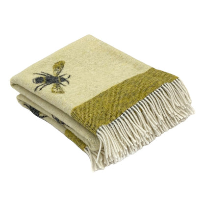 Folded beige and green blanket with a bee design on a white background