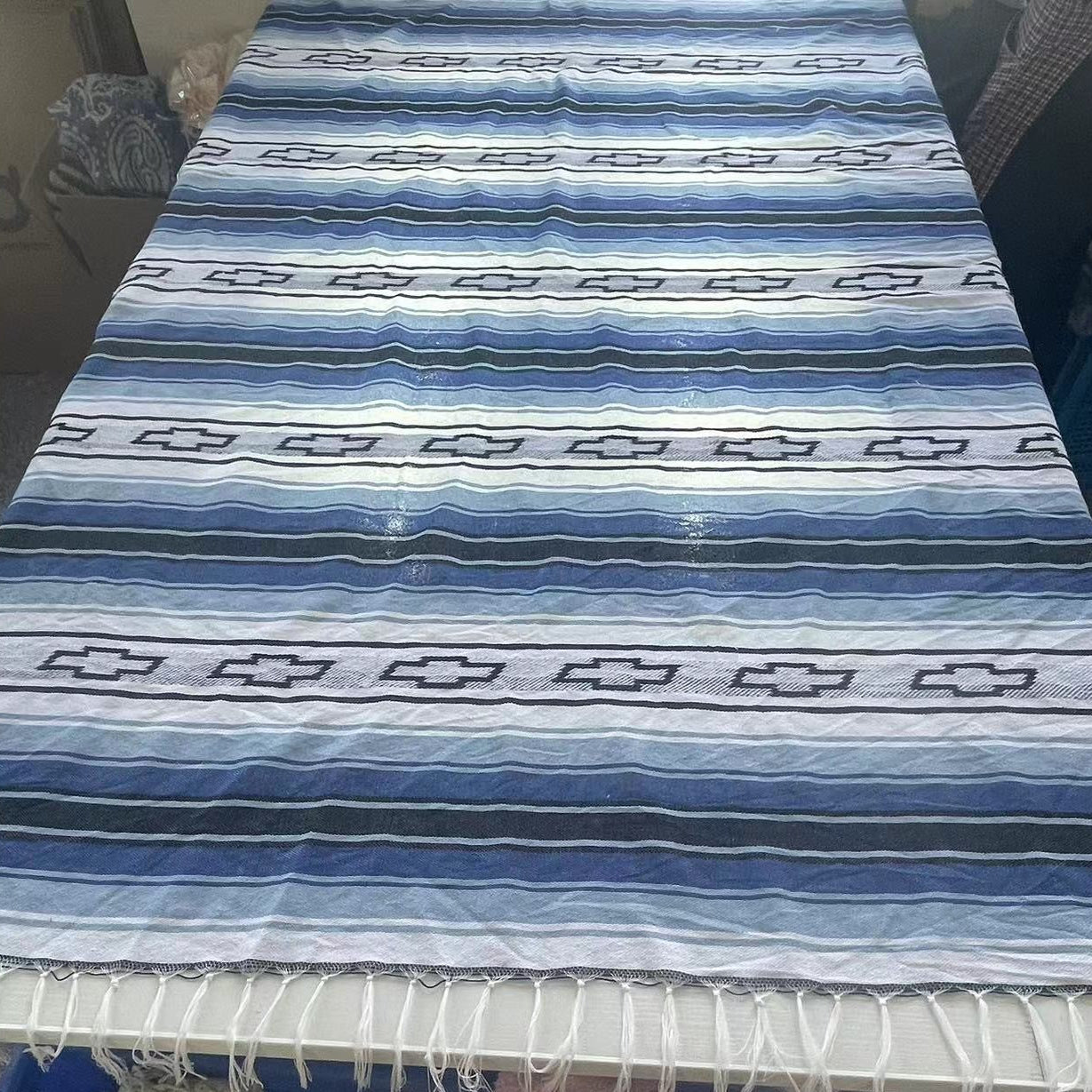 Blue and white mexican falsa blanket custom serape blanket with geometric pattern on a table.