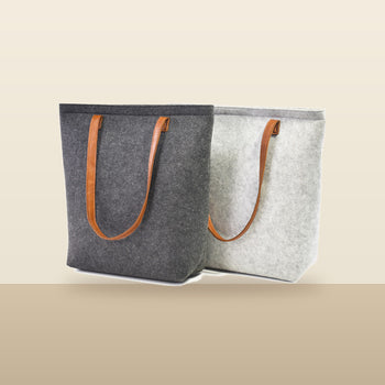 Charcoal and Light Gray Bellagio wool totes on a warm sand backdrop